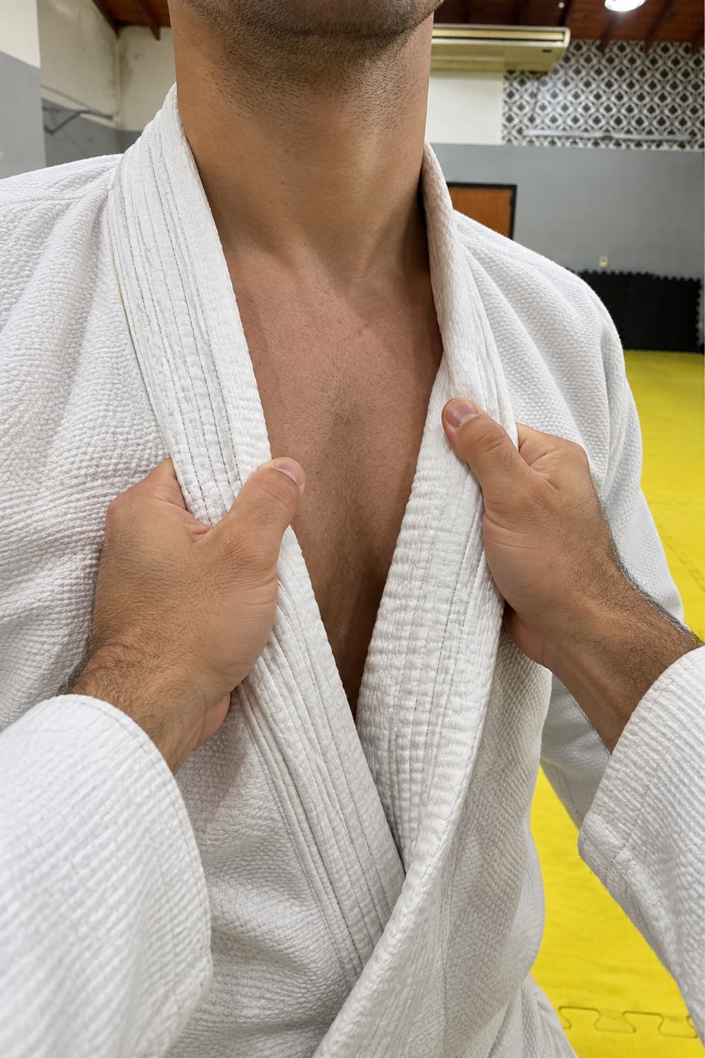 Manos tomando el cuello de un gi blanco.
